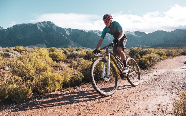 mountain biker racing down a jeep track outside of Cape Town South Africa with snow capped mountains in the background